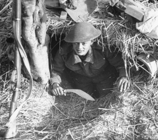 Blandiendo su Kukri, un soldado gurkha sale de una trinchera, en algún lugar en el sector de Ortona durante el empuje aliado para expulsar a los alemanes de Italia