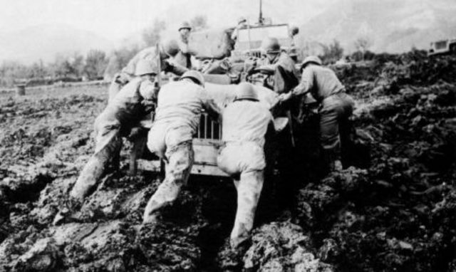 Soldados norteamericanos empujando un jeep atascado en el barro