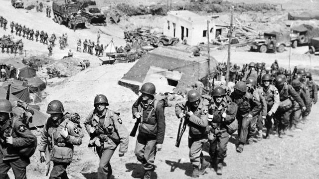 Refuerzos de la 2ª División de Infantería de los EE.UU. marchan por una colina cerca de un bunker alemán el 6 de junio de 1944