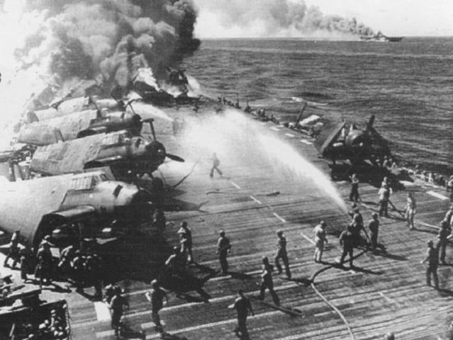 El equipo de control de daños del portaaviones ligero Belleau Wood intentando controlar el fuego después de un ataque kamikaze