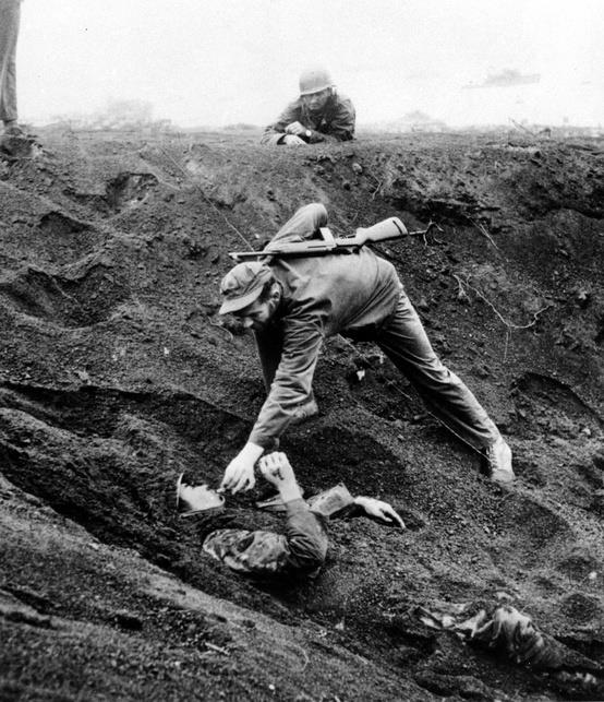 Un soldado norteamericano da un cigarrillo a un japonés semienterrado, durante los bombardeos de Iwo Jima, 1945